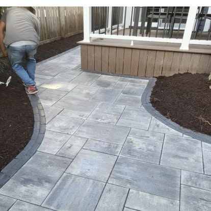 A paver patio and seat wall under construction.